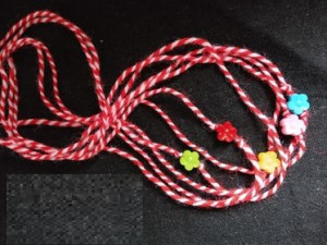 MARTENITZA für Hand mit Perle (5 Stück) sind traditionelle bulgarische kleine Handgelenksbänder oder -schmuckstücke, handgefertigt aus roter und weißer Wolle, typischerweise mit kleinen Perlen oder Holzperlen versehen. Diese symbolisieren Gesundheit, Glück und den Frühling und werden zum Marteniza-Fest am 1. März getragen, um den Winter zu vertreiben und den Frühling zu begrüßen. Die Wolle ist weich und angenehm zu tragen, und die Perlen sorgen für eine zusätzliche dekorative Note. Diese Martenitzas sind handgearbeitet und werden oft als Geschenk oder Glücksbringer verwendet.