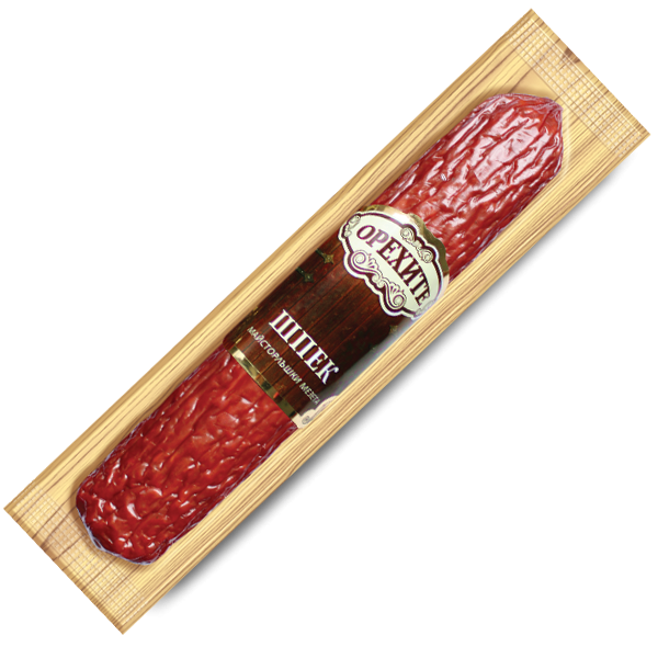 The image shows a packaged sausage product. The sausage is reddish in color with a textured surface and is enclosed in a clear plastic wrapper. The label on the packaging includes ornate design elements and Russian text that reads ОРЕХОВЪ and ШПЕК, with some additional smaller text. The packaging has a wooden plank-like design surrounding the sausage.