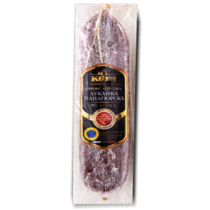 The image shows a packaged sausage. It is enclosed in clear plastic, showcasing a dark, possibly cured sausage. The label on the packaging features Cyrillic text in white, with some highlighted elements in gold and red. There is also a circular emblem at the bottom, likely indicating quality or origin. The design suggests a premium product.