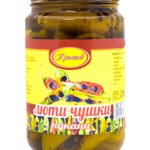 The image shows a jar of pickled peppers. The jar has a red lid and a colorful label with yellow as the primary background color. The label features an image of vibrant, multicolored peppers and includes text in a language that appears to be Cyrillic. The peppers inside the jar are visible through the glass, partially submerged in brine.