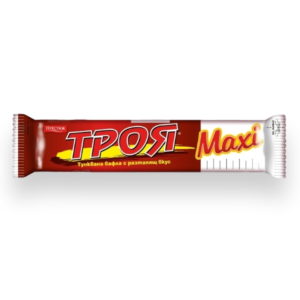 The image shows a wrapper of a confectionery product. The packaging is predominantly red with white and yellow accents. The text features bold, stylized letters in both Cyrillic and English, prominently displaying the word Макси (Maxi). Additionally, there is a small logo in the top left corner. The design suggests it's a wafer product,