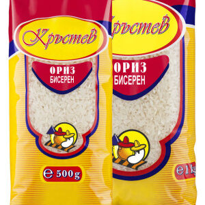 The image shows two packages of rice with a red and yellow design. Both packages feature a transparent window revealing the rice inside and have similar branding. The top section of the packaging has a yellow oval with decorative text. Below the window, there is an illustration of a cartoon character. One package is labeled 500g while the other is labeled 1 kg, indicating their respective weights.