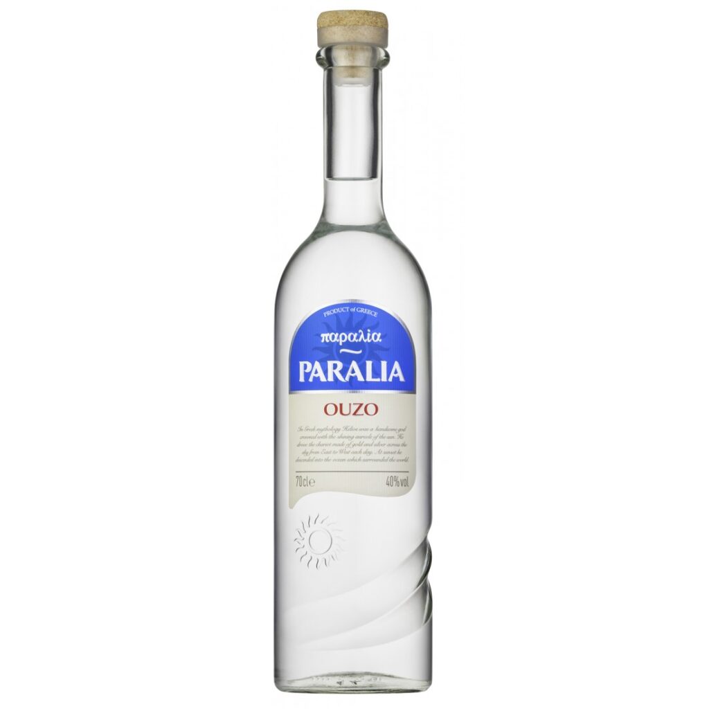 The image shows a tall, clear glass bottle of Paralia Ouzo. The bottle has a straight neck with a cork stopper. The label is primarily blue and white, featuring the text Paralia prominently in blue and OUZO in red below it. The label also includes Product of Greece. The bottle is 700 ml with an alcohol volume of 40%. The design is sleek with subtle swirl patterns near the base and a small sun icon.