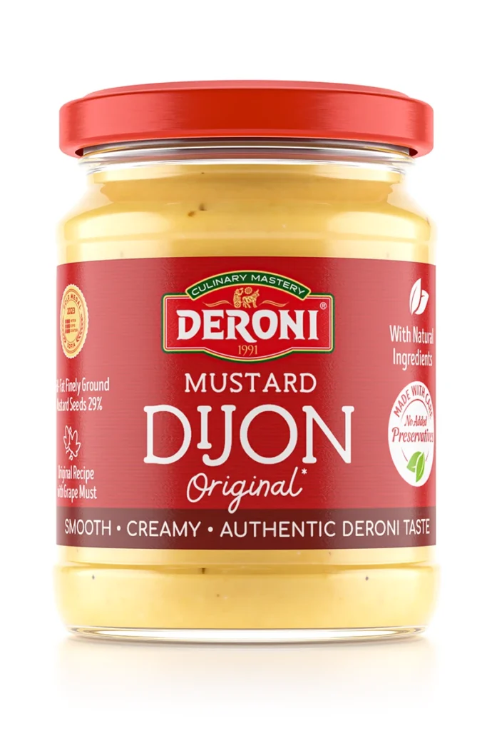 The image shows a glass jar of Deroni brand Dijon mustard. The jar has a red lid and a label with a red background. The words Culinary Mastery and 1991 are featured prominently along with the brand name Deroni. The label describes the mustard as Original Dijon Mustard and highlights it as Smooth, Creamy, Authentic Deroni Taste. Additional text notes that it's made with natural ingredients and without added preservatives. The mustard inside is yellow.