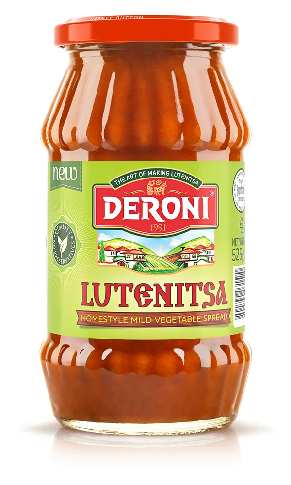 This image shows a jar of Deroni Lutenitsa, labeled as a Homestyle Mild Vegetable Spread. The jar has a distinctive shape with a red lid and a green label. The label features the brand name Deroni in large white letters on a red background, with the year 1991 beneath it. An illustration of a countryside scene with houses and hills is also included. The label notes that the product is new, with no preservatives, and contains 525 grams.