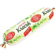 The image shows a log-shaped package of food, labeled with Cyrillic text. The packaging is in predominantly light green with red accents, featuring the word Класик prominently. There are decorative elements, like leaves, on the wrapper. The package is sealed at both ends.
