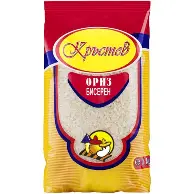The image shows a packet of rice. The packaging is mostly red and yellow with some blue accents. There's a large oval label at the top with text in a script-like font. Below it is the text ОРИЗ БИСЕРЕН. Near the bottom, there's a circular logo featuring an illustration of a character holding a fork and spoon.