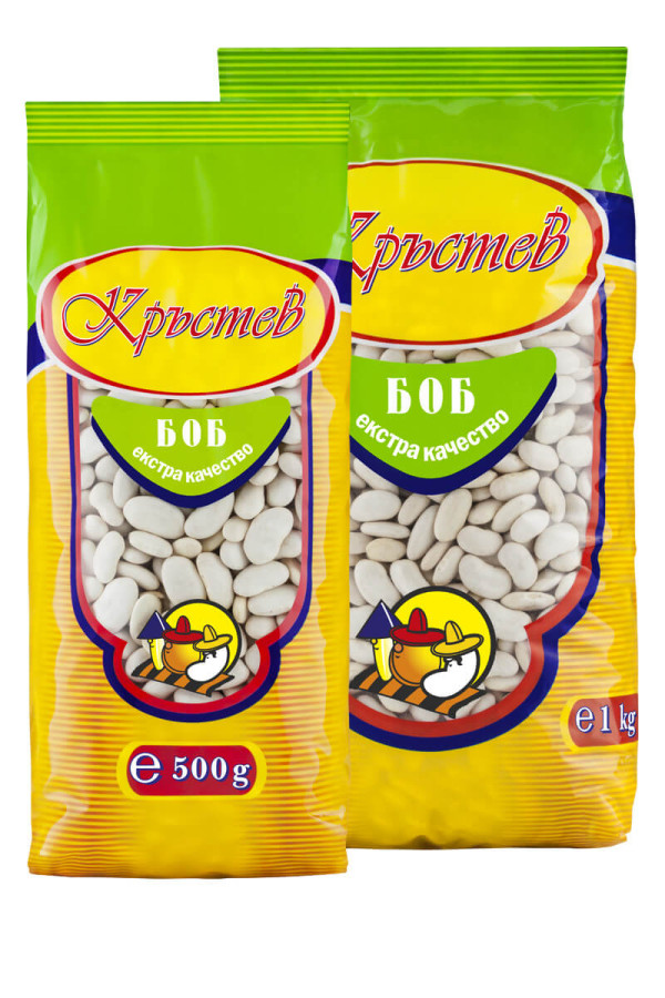 The image shows two bags of white beans from a brand with a Cyrillic label. The packaging is primarily yellow and green with the brand name in red. Each bag features a transparent section showing white beans inside. A colorful cartoon character, resembling a construction worker, is depicted on the front. There are two different sizes: one bag is 500 grams and the other is 1 kilogram, with respective labels on the bottom.