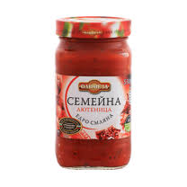 The image shows a jar of Cormen Family Lutenitsa. The jar is filled with a red sauce, commonly used in Bulgarian cuisine. The label on the jar is white with red and black text, featuring the brand name and type of product. The lid is also red with some green detailing.