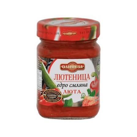 The image shows a jar of Ljutenica, a type of Balkan red pepper and tomato relish. The jar has a red lid and a colorful label featuring images of vegetables like peppers and tomatoes. The text on the label appears to be in Cyrillic script.