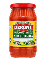 The image is of a jar of Deroni brand traditional lyutenitsa. The jar is made of glass and has a red plastic lid. The label is predominantly yellow with the brand name Deroni in bold red lettering at the top. Below, there's text in another language, likely describing the product as traditional lyutenitsa. The label also features imagery of a countryside landscape with houses.